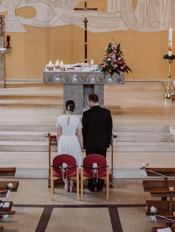 Ein Brautpaar steht in einer Kirche vor den Stufen des Altars.